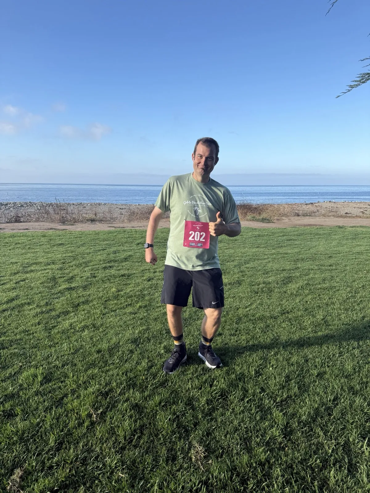 Kevin after a race, thumbs up on the beach in bib 202